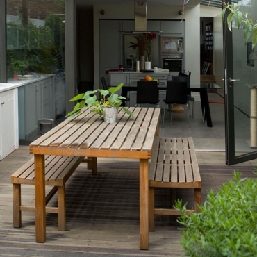 low-maintenance garden ideas with benches and a table on a deck