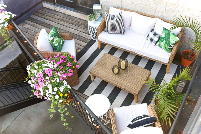 a top-down view of a small balcony with furniture, rigs and overflowing flowers