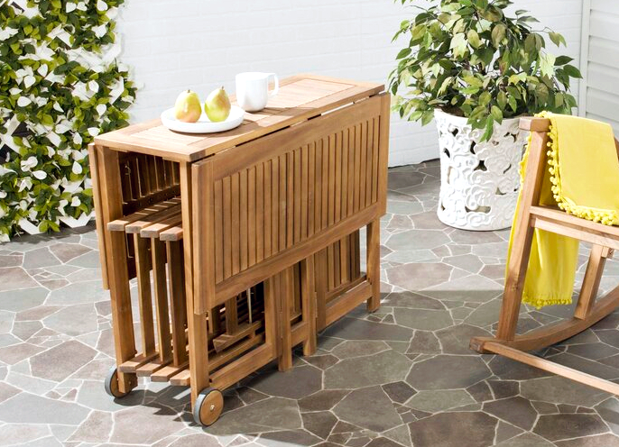 a wooden drop-leaf table with four folded up chairs stored under it
