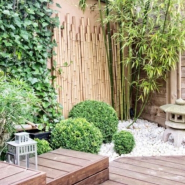 A small, Japanese-inspired garden with decking, box shrubs, pebbles and lanterns