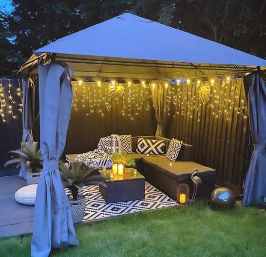 a gazebo with the sides open to reveal a curtain of pretty fairy lights, an easy way to transform your garden on a budget