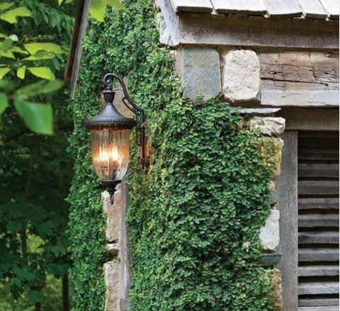 a black metal lantern on the outside of a rustic stone building