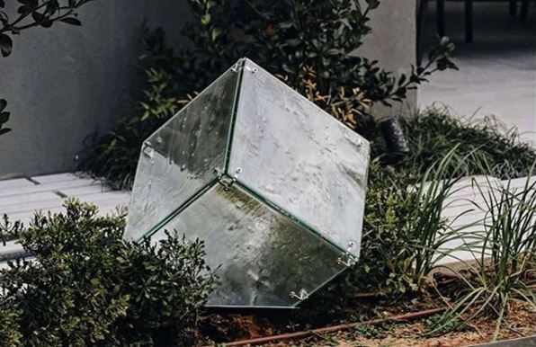 a transparent, cube shaped light in a flower bed