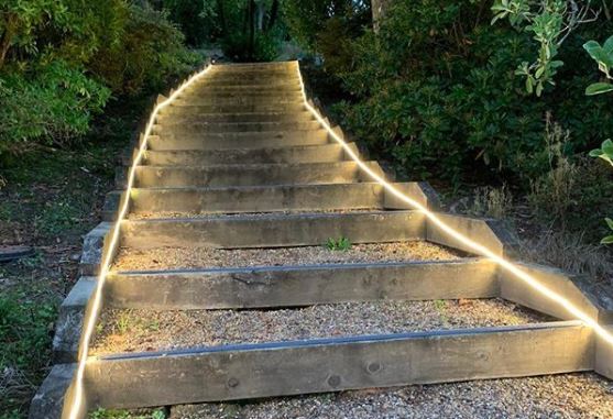 a set of shallow gravel garden steps with LED cable lighting running up either side
