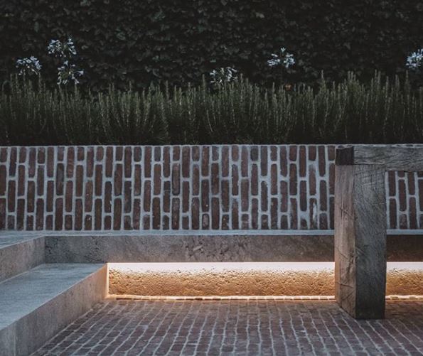 a concrete bench in front of a weathered brick wall on a weathered brick patio