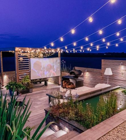 a tidy garden deck over two levels, with pretty garden pond lighting and home cinema screen