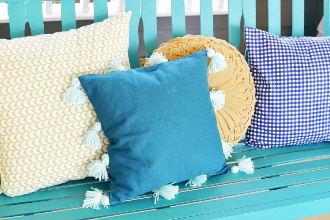 A bench with assorted cushions, including one in blue velvet with pretty white tassles