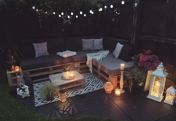 A corner sofa made from stacked pallets surrounds a coffee table, also made from pallets
