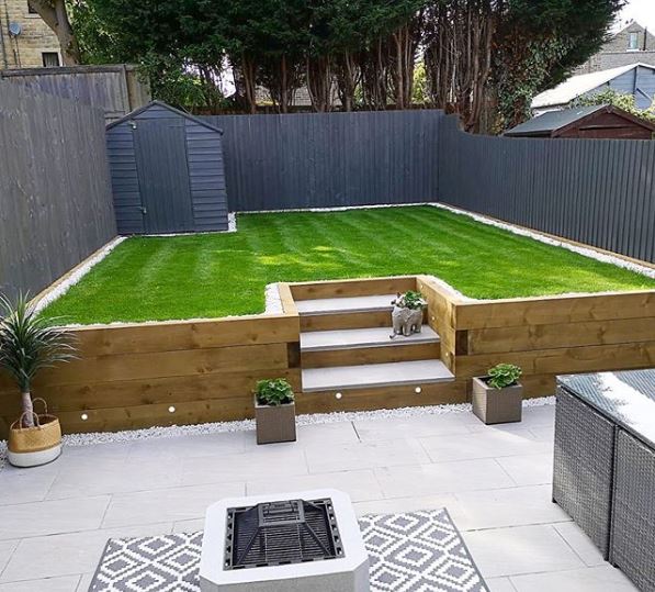 A tidy garden with a patio area and steps leading up to a raised lawn made from AstroTurf