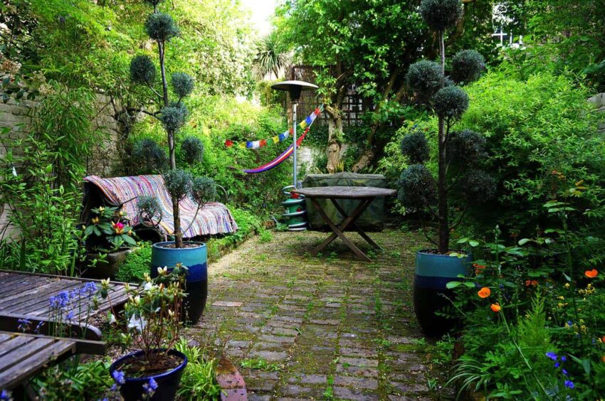 Bohemian garden with mossy cobblestones and slightly overgrown flower beds