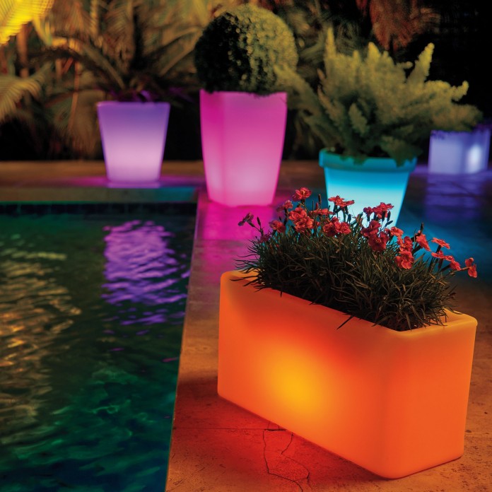 solar-powered planters lit up in various colours around the edge of a pool