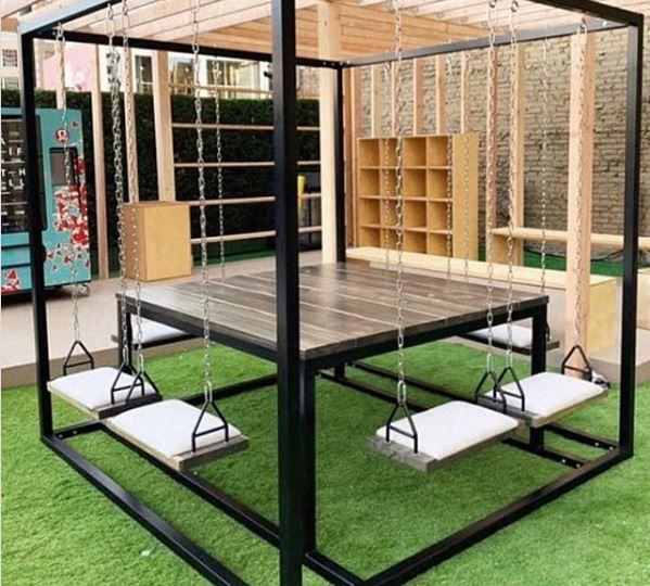 a black frame supports eight swings all facing a central dining table