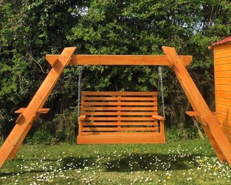 A sturdy swing bench made from orange-stained wood