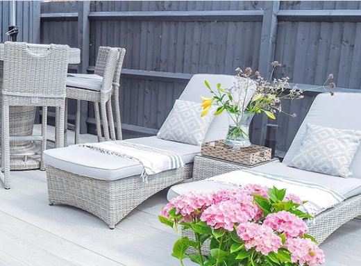 Two grey rattan loungers with grey blankets and cushions