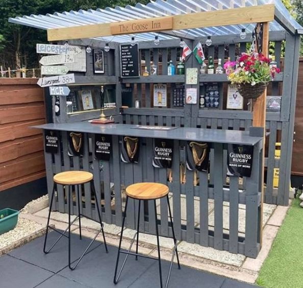 a DIY garden bar made from pallets with a clear plastic roof