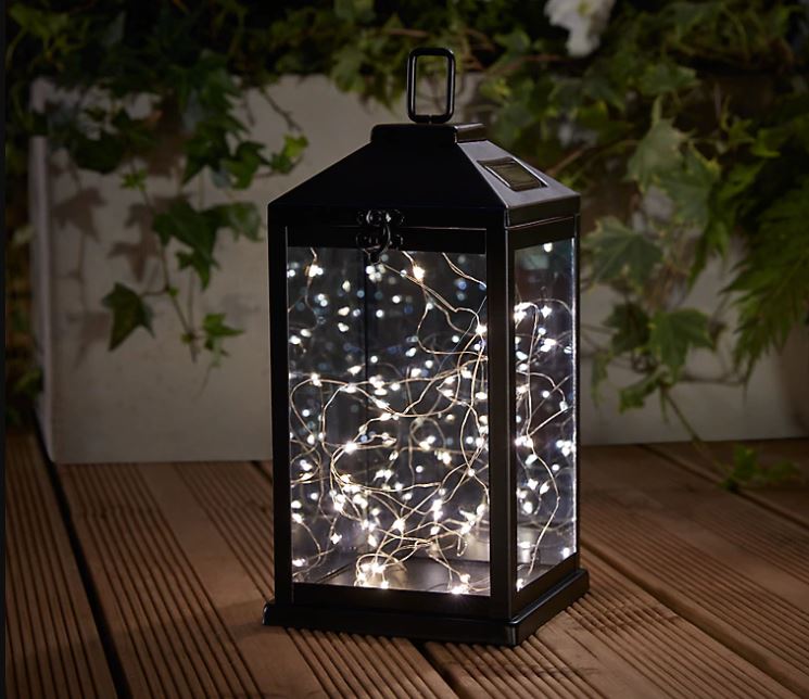 a black metal lantern filled with pretty fairy lights