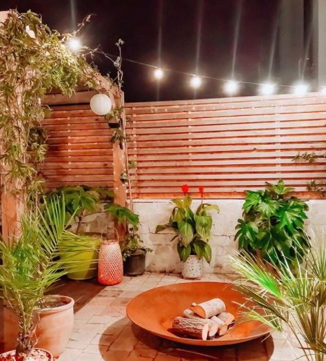 8 Morocco Garden Ideas to Design Your Own Moroccan Courtyard 10 a courtyard garden with potted plants, wooden fencing and a large fire bowl