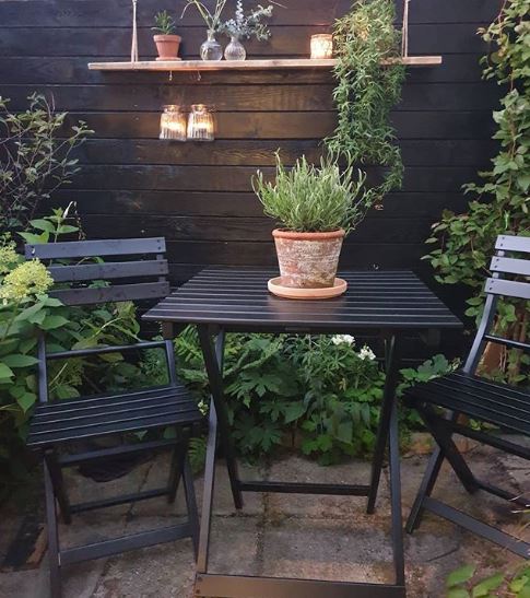 a fold-up set of table and chairs in matte black, on a leafy patio