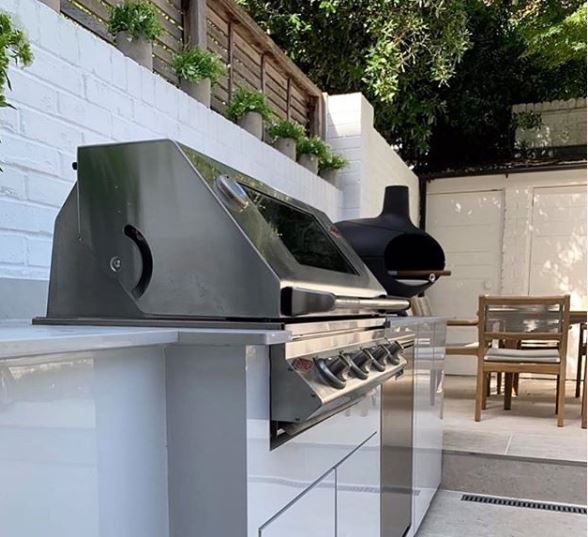 a modern outdoor kitchen with a stainless steel in-built BBQ grill