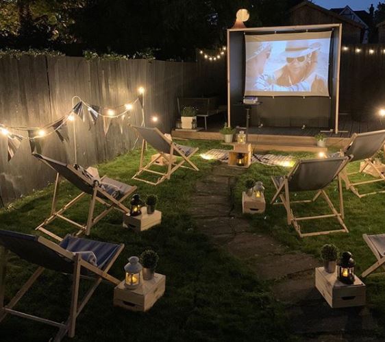 a night-time cinema set up with deck chairs and string lighting