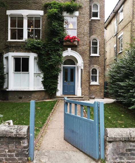 a pale blue gate opens onto a pathway leading to a matching blue door