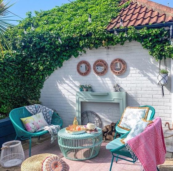a patio with rug, chairs and coffee table, featuring a fireplace frame leaning against the rear wall