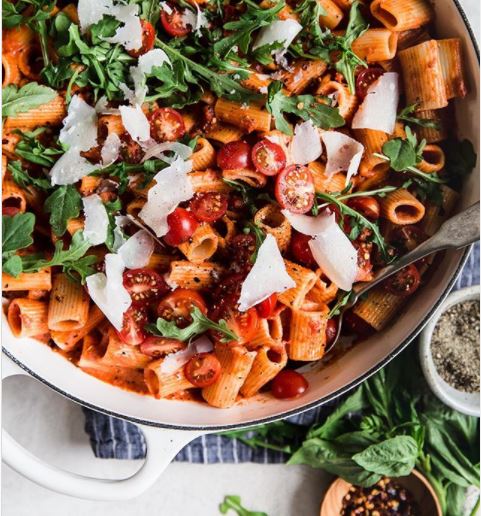 a pot of pasta with cherry tomatoes, rocket and herbs