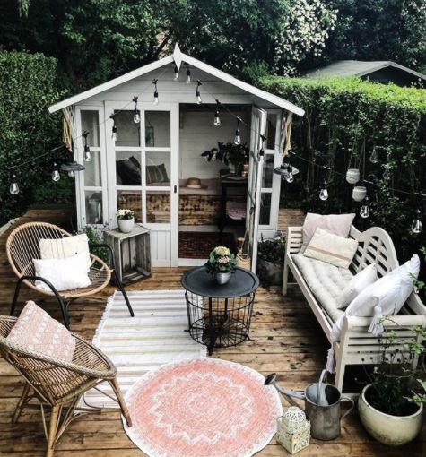 40 Garden Shed Ideas for Pretty to Practical Outdoor Buildings 29 a pretty she shed with glass doors opens onto a deck with chairs, bench and outdoor rugsx