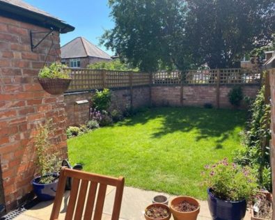 a rectangular lawn in a small garden with a border of plants and flowers
