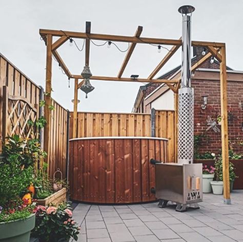 a round, scandinavian style hot tub with wood panelling under a pergola