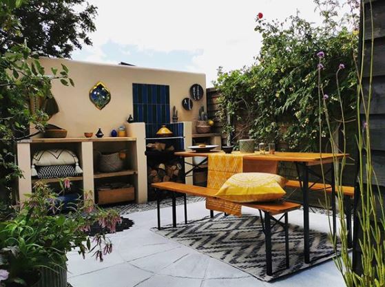 8 Morocco Garden Ideas to Design Your Own Moroccan Courtyard 6 a small courtyard garden painted yellow, with a picnic table, rugs and cushions