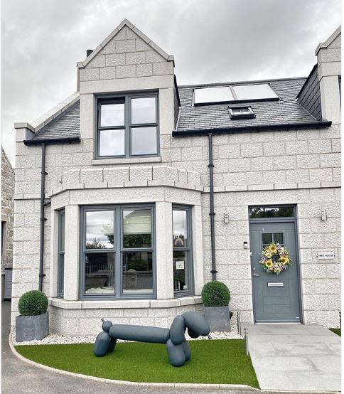 a small front garden covered with artificial grass with a large lawn concrete ornament shaped like a balloon animal