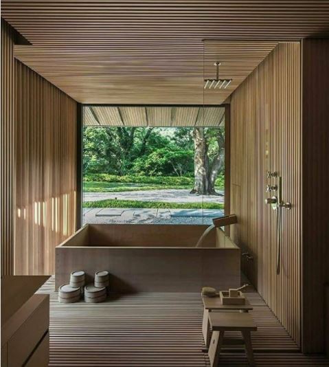 a square japanese style bath in a room with narrow wood panels and large windows that make it feel like it's outside