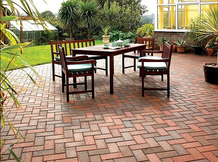 a very clean patio made from paving block in red and brown, laid in a herringbone pattern