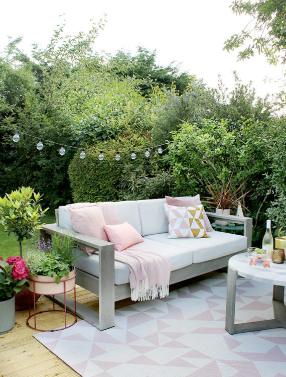 a white and grey outdoor sofa with pink cushions, on a pretty white and pink rug