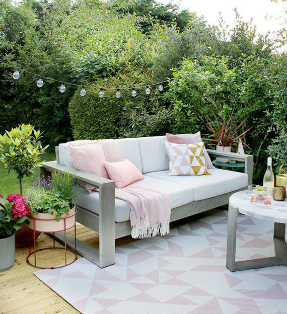 a white and grey outdoor sofa with pink cushions, on a pretty white and pink rug