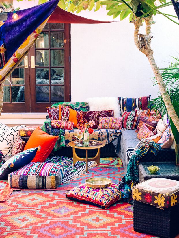 an outdoor seating area crammed with bright cushions and rugs in embroidered fabrics