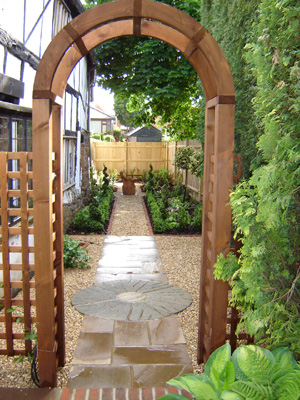 archway leading into a narrow garden with a path running all the way down the middle