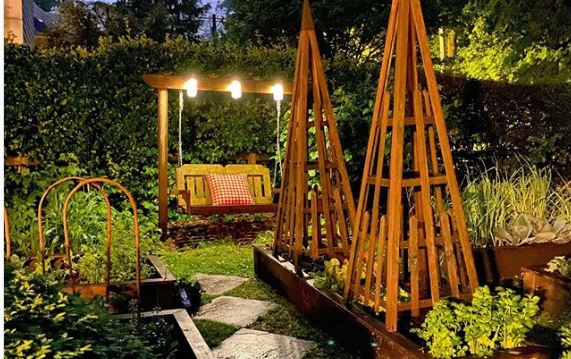 a rustic wooden swing bench with three bright overhead lights attached