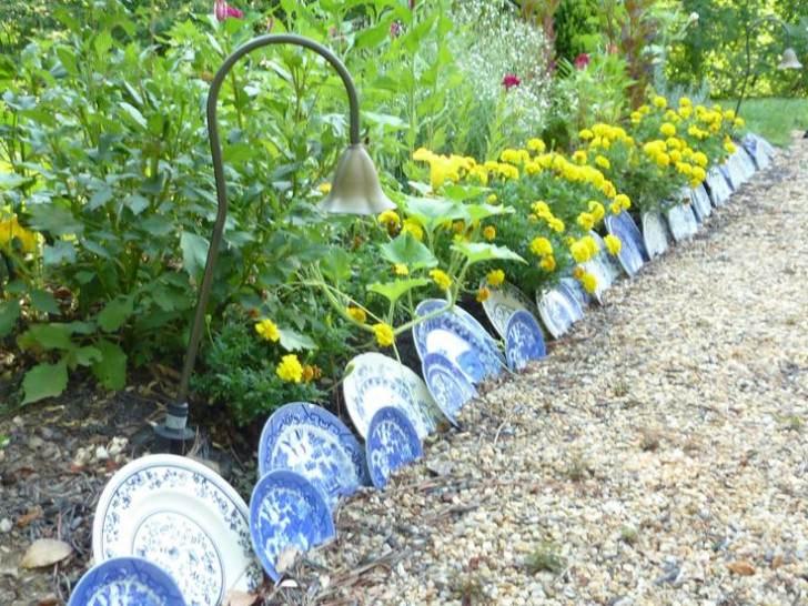 The Secret to a Manicured Landscape: 16 Garden Lawn Edging Ideas 5 a flower bed edged with blue pattered ceramic plates in various sizes