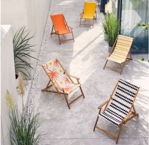 five brightly coloured deck chairs are staggered across a concrete patio