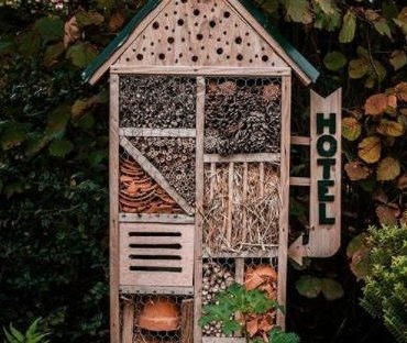 garden bug hotel ideas - a small insect hotel with a little hotel sign on the side