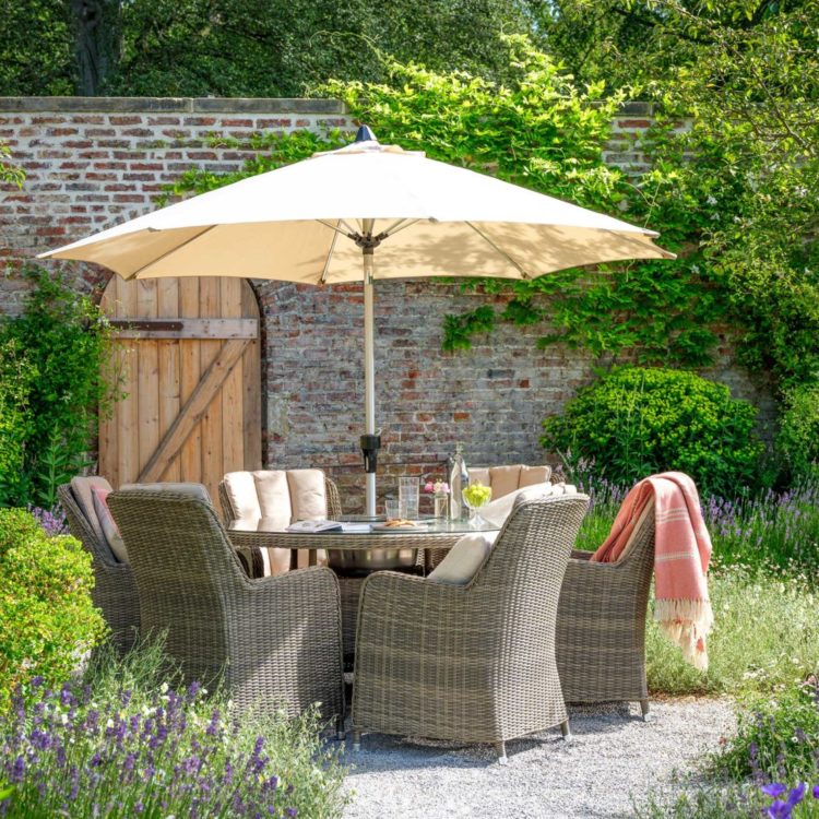 Timeless rattan chairs around a glass-topped table, under a parasol