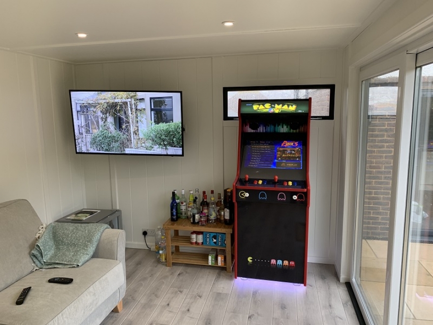 23 Cool Garden Man Cave Ideas to Pimp Your Outdoor Shed 3 garden man cave with pacman arcade machine, sofa and shelves with a variety of alcohol bottles