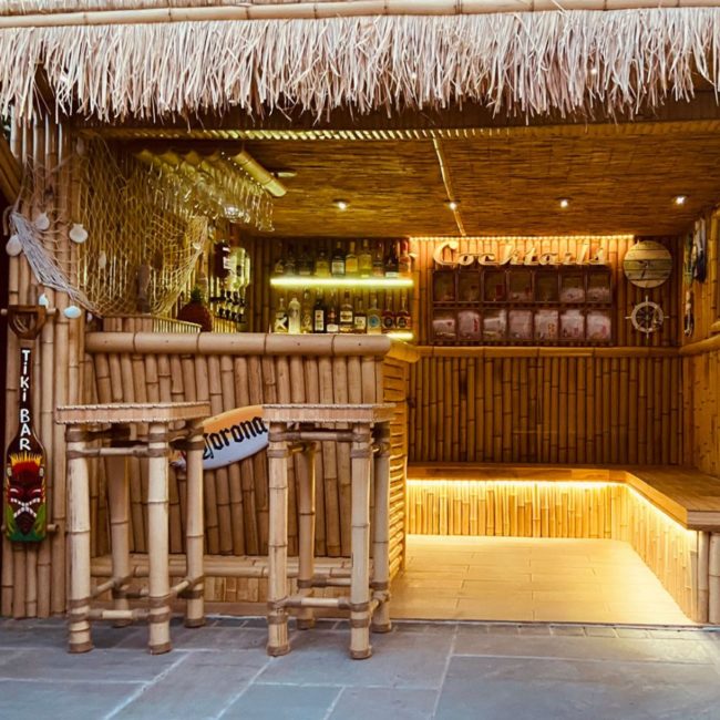 a tiki style garden bar made from bamboo with a grass roof