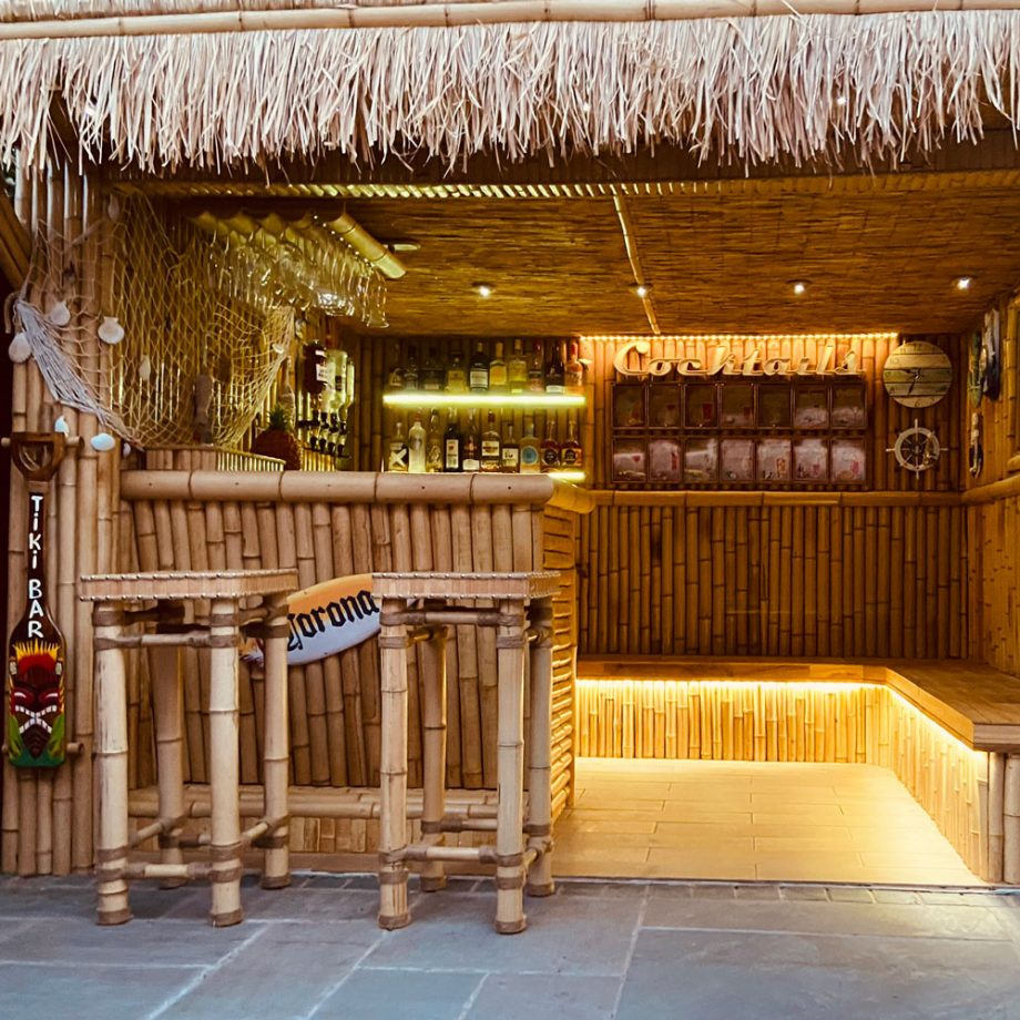 a tiki style garden bar made from bamboo with a grass roof