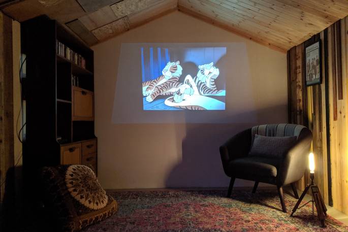 40 Garden Shed Ideas for Pretty to Practical Outdoor Buildings 34 inside a garden man cave with a projector, playing an animated film