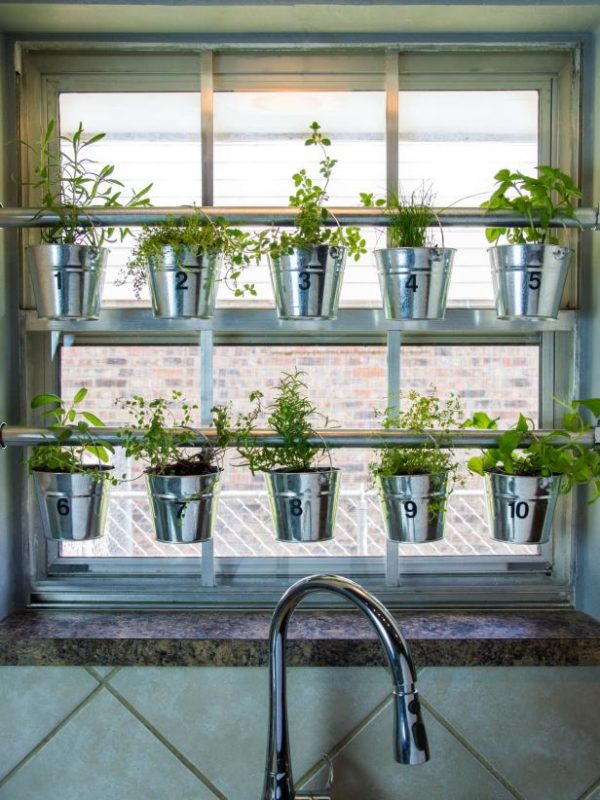 kitchen garden ideas - two rails across a kitch window with pots of herbs hanging from them