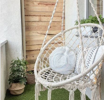 a macrame swing hanging on a small balcony