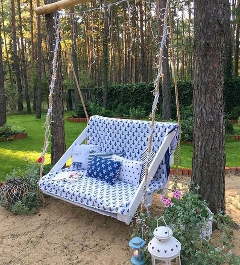 A wooden swing covered in a blanket with an anchor pattern and co-ordinating cushions